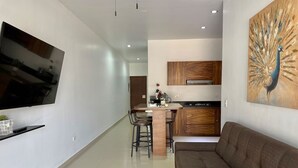 Ein modernes Wohnzimmer mit Flachbildfernseher, einer Couch und einem Essbereich mit Stühlen und einem Tisch.