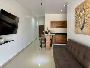 A modern living room with a flat-screen TV, a sofa, and a dining area with chairs and a table. - Torre Toronto Zona Dorada by GPS (Mazatlán)