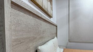 Ein Schlafzimmer mit einem hölzernen Kopfteil, einem Bett mit orangefarbener, strukturierter Bettdecke und einem weißen Kissen.