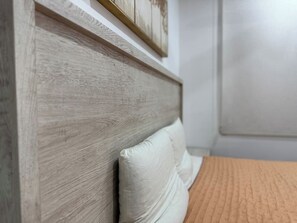 A bedroom with a wooden headboard, a bed with a textured orange bedspread, and a white pillow. - Torre Toronto Zona Dorada by GPS (Mazatlán)