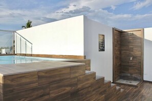 A modern outdoor pool area with a wooden deck, a glass enclosure, and a wooden shower enclosure. - Torre Toronto Zona Dorada by GPS (Mazatlán)