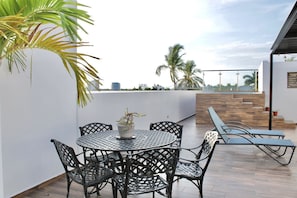 A rooftop terrace with a round table and chairs, a potted plant, and a view of palm trees and buildings. - Torre Toronto Zona Dorada by GPS (Mazatlán)