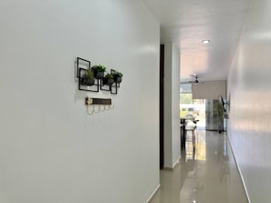 A hallway with a white wall, a black wall-mounted shelf with plants, and a 'HOME' sign. - Torre Toronto Zona Dorada by GPS (Mazatlán)