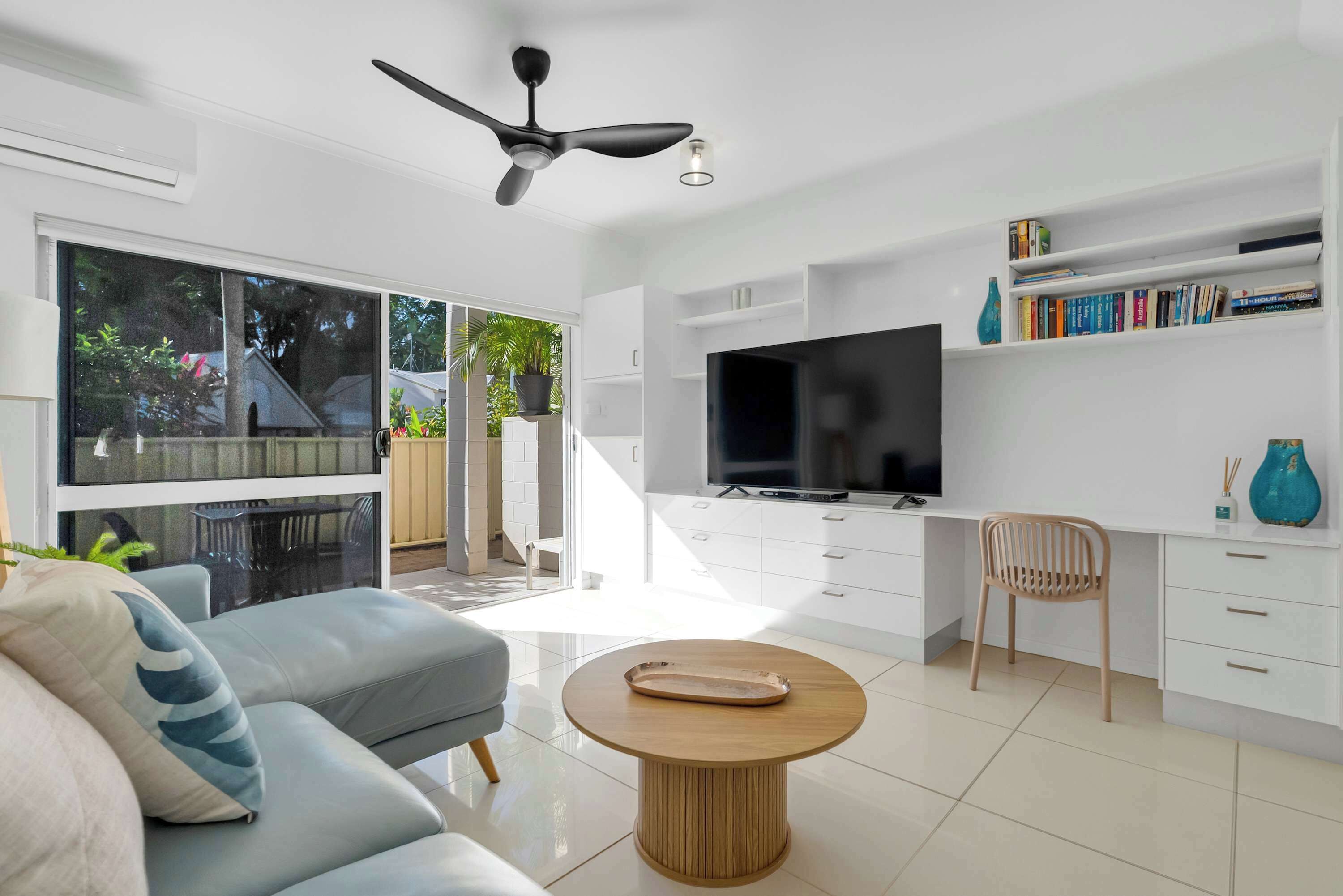 A modern living room with a sofa, a coffee table, a TV, and a bookshelf.