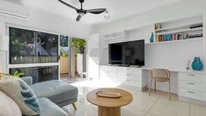 Un salon moderne avec un canapé, une table basse, un téléviseur et une bibliothèque.
