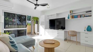 A modern living room with a sofa, a coffee table, a TV, and a bookshelf.