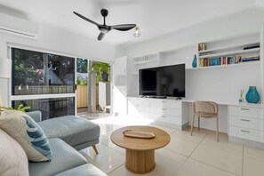 Una sala de estar moderna con un sofá, una mesa de centro, un televisor y una estantería.
