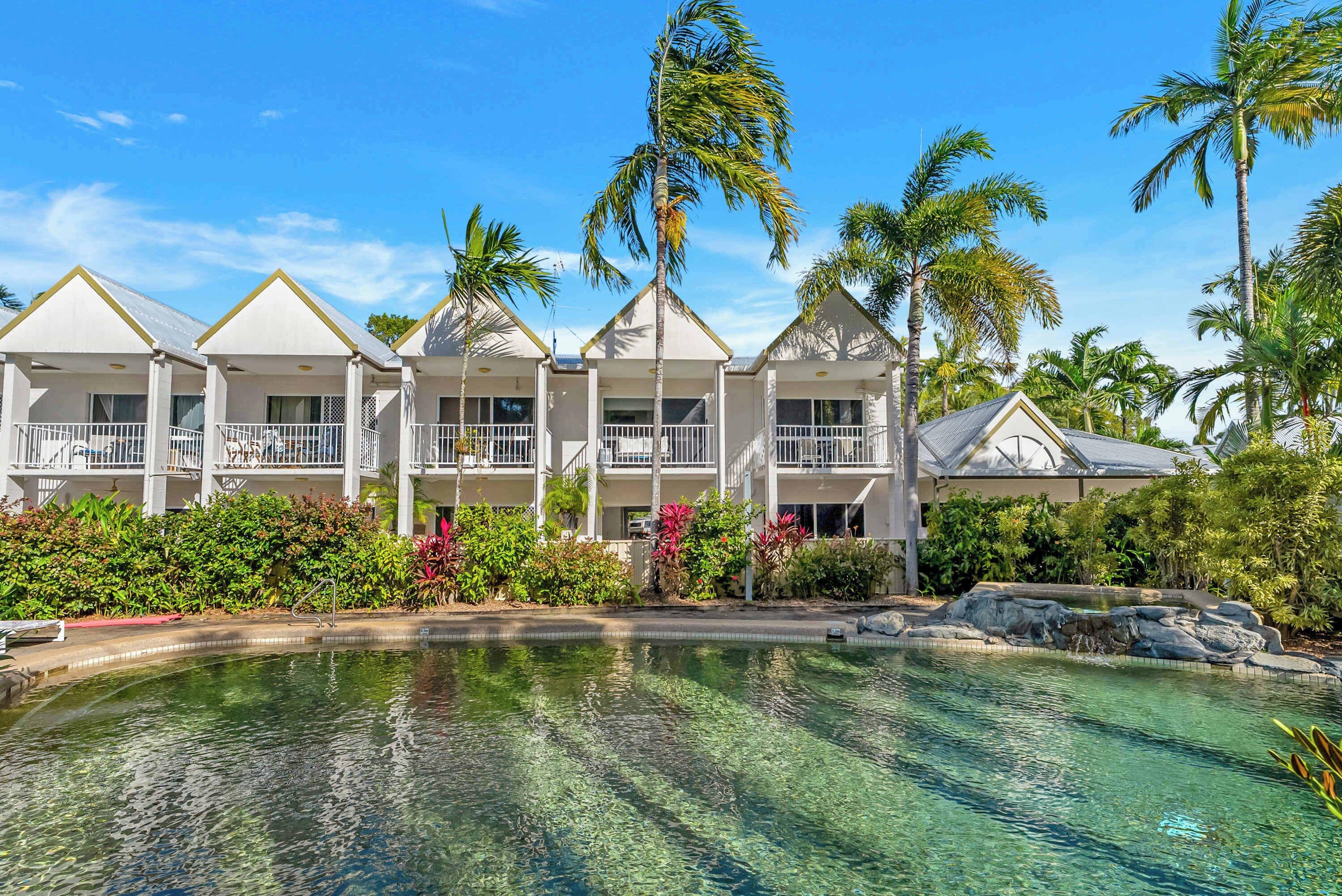 A resort with a pool, multiple-story buildings, and palm trees.