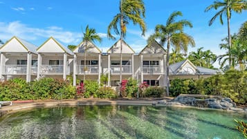 A resort with a pool, multiple-story buildings, and palm trees.