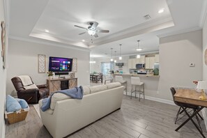 A modern living room with a sofa, TV, and ceiling fan. - Hot Tub/Fire Pit/Star Wars Room/Military Friendly (Navarre)