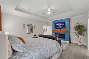 A bedroom with a large bed, a ceiling fan, a mounted TV, a fireplace, and a potted plant. - Hot Tub/Fire Pit/Star Wars Room/Military Friendly (Navarre)
