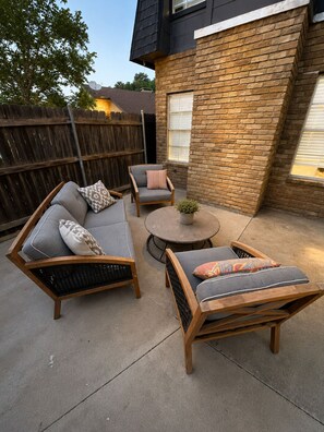 Eine Terrasse mit zwei Sofas, einem runden Tisch und einem kleinen Topfpflanzen.