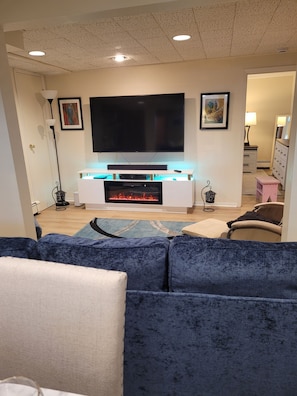 Una sala de estar con televisión de pantalla plana, chimenea, sofá y mesa de centro.