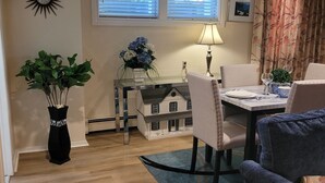 Un comedor con una mesa, sillas, una lámpara, una planta en maceta y una maqueta de una casa.