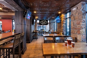 A restaurant interior with wooden tables and chairs, stone walls, and a sign reading 'Drafts.' - Westgate Park City Resort & Spa (Park City)