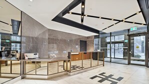 Et moderne receptionsområde med marmorgulv, glasvægge og en receptionsdisk.