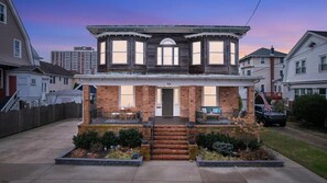 A two-story house with a front porch, a brick facade, and a number '52' on the front door.