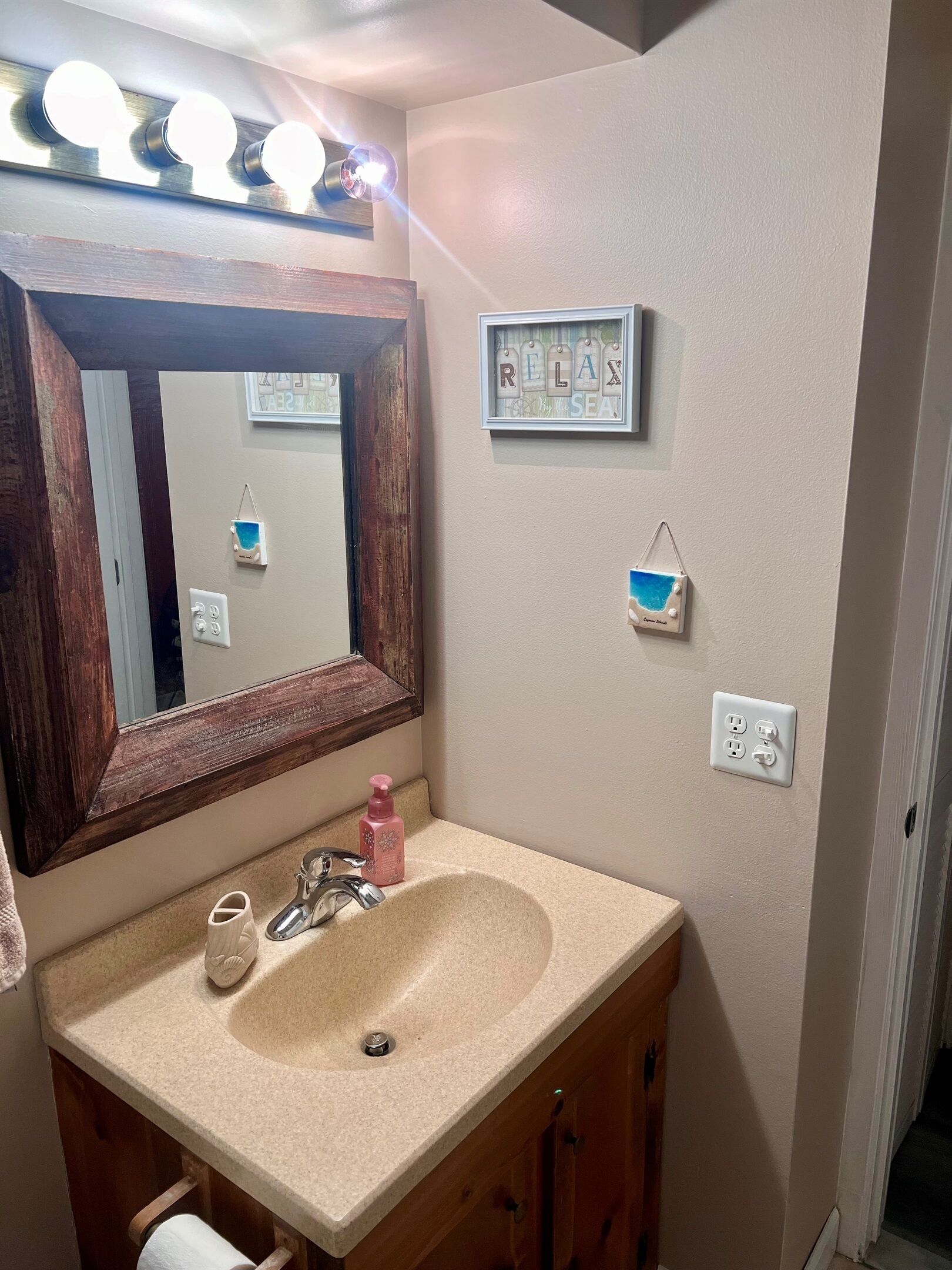 Un bagno con uno specchio grande, un lavandino, un mobile bagno e un portalampada a parete.