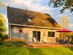 A house with a 'WELCOME' sign, a star decoration, and a deck with chairs and a table.