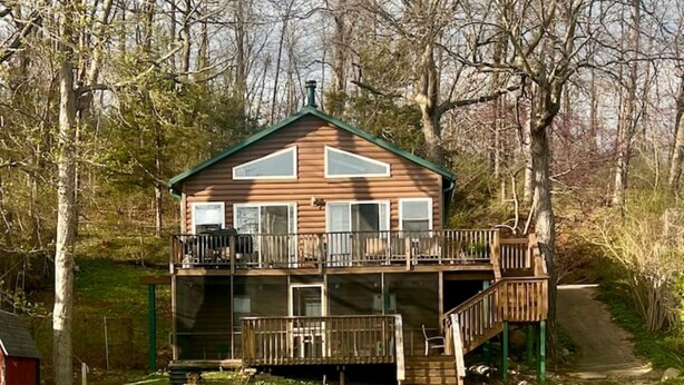 A two-story wooden cabin with a balcony, a staircase, and a small porch area.