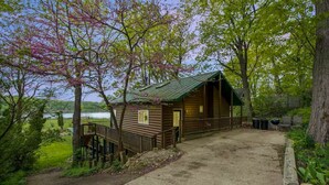 Eine rustikale Holzhütte mit einer Holzterrasse, einer Veranda und einer Schotterzufahrt.