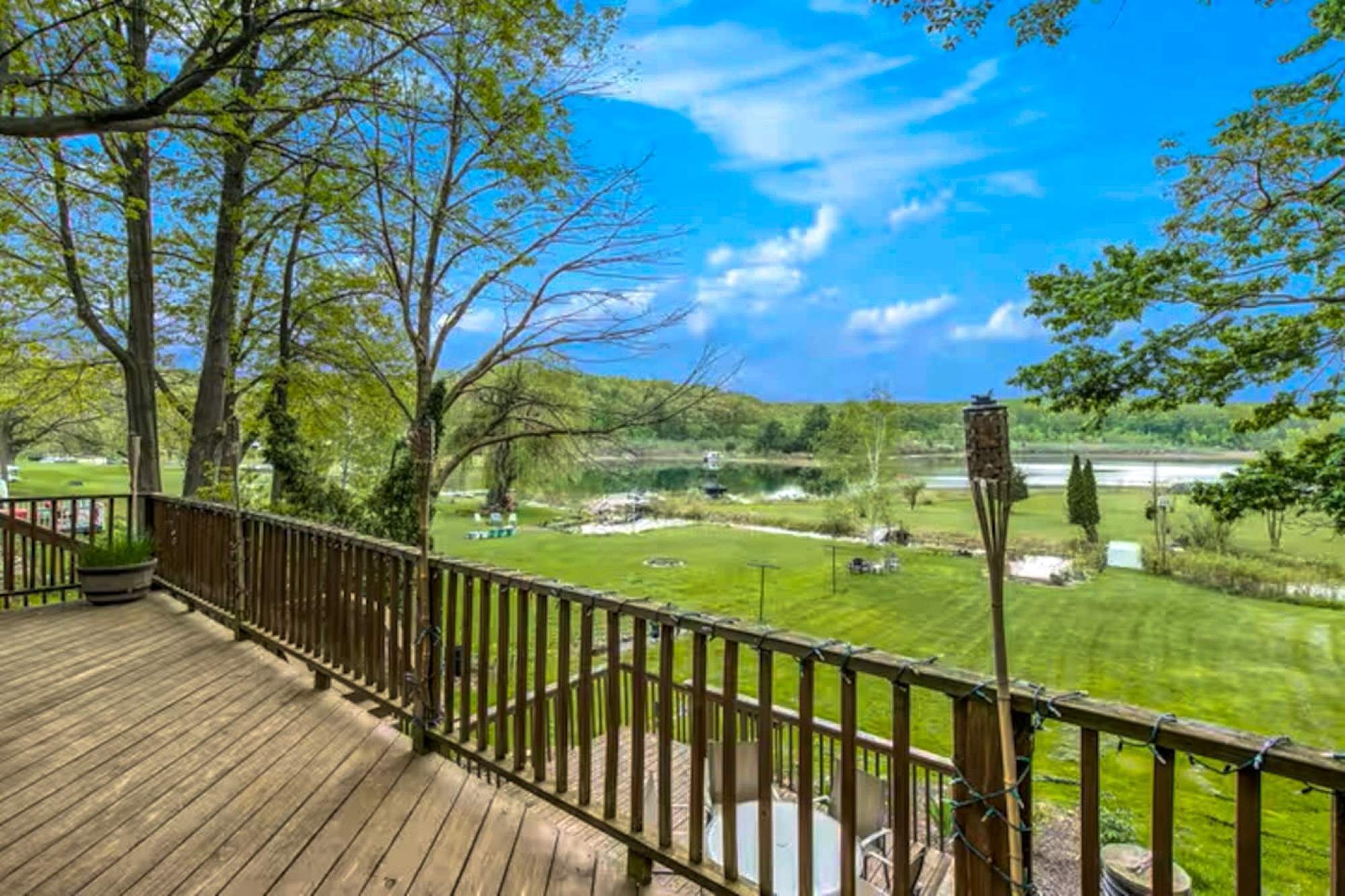 A wooden deck with a view of a golf course and a lake.