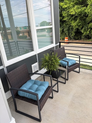Ein Balkon mit zwei Korbstühlen, jeweils mit einem blauen Kissen, und einem Blumentopf.