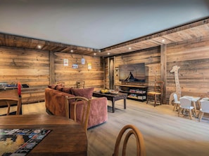 Una sala de estar acogedora con pared de madera, televisor, decoración de jirafa y un juego de mesa.