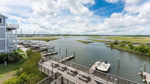 A waterfront property with a dock, a boat, and a building with a balcony. - Waterfront Paradise, 5BR, Elevator, Expansive Decks & Views (Surf City)