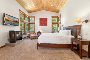 A bedroom with a bed, a fireplace, a TV, and large windows. - Monthly Lease - Granite Peak at Palisades - Tahoe Getaways - 4BR Dog Ok w Hot Tub & Shuttle (Olympic Valley)