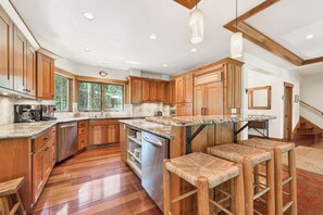 A spacious kitchen with wooden cabinets, a granite countertop, and a built-in dishwasher. - Monthly Lease - Granite Peak at Palisades - Tahoe Getaways - 4BR Dog Ok w Hot Tub & Shuttle (Olympic Valley)