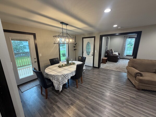 A dining area with a table set for four, a sofa, and a chair in a living room.
