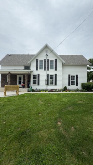 A two-story house with a front porch, a brick section on the left, and a well-maintained lawn.