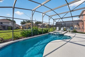 Una piscina con zona cubierta, rodeada de casas, y cielo despejado.