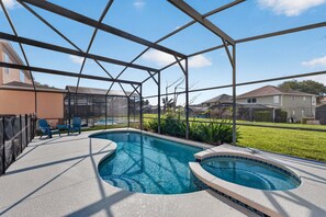 Una piscina con una estructura de sombrilla, un área de descanso con sillas y vista a casas vecinas.