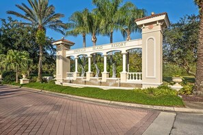 Ein begrenzter Zugangsbereich mit der Beschilderung 'Emerald Island Resort', Palmen und einem gepflasterten Weg.