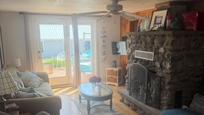 A living room with a stone fireplace, a sofa, a coffee table, and a television.