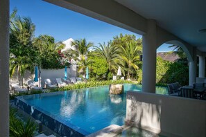 Une piscine entourée de palmiers et de verdure, avec des chaises longues et des parasols.