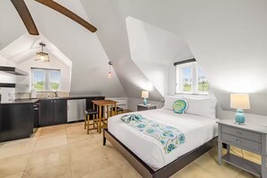 Ein modernes Loft-Schlafzimmer mit einem großen Bett, einer kleinen Küchenzeile und einem Esstisch.