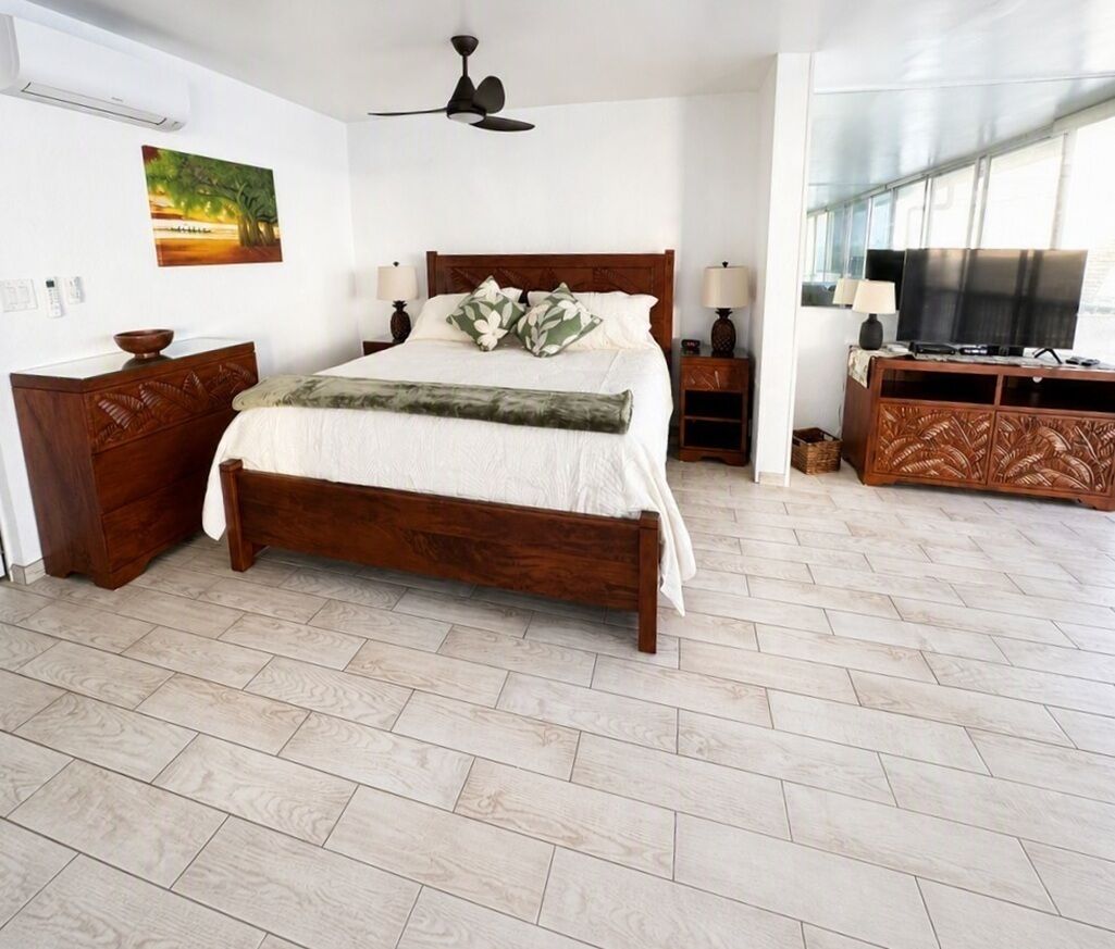 Un dormitorio con una cama de madera, televisión y ventana.