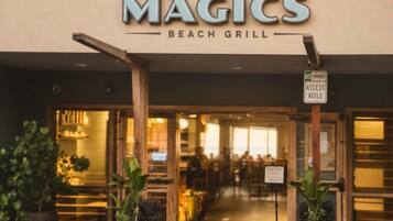The exterior of a beach grill named 'MAGICS' with a 'NO PARKING ACCESS AISLE' sign.