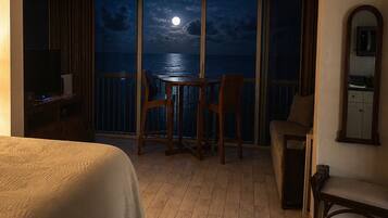 A hotel room with a balcony, a bed, a table, and chairs.