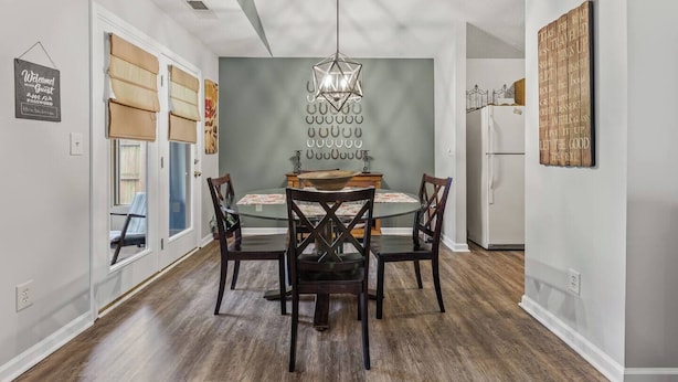 A dining area with a table and chairs, a hanging light fixture, and a wall with a decorative pattern. - 7 Miles to Horse Park/ King Size (Georgetown)