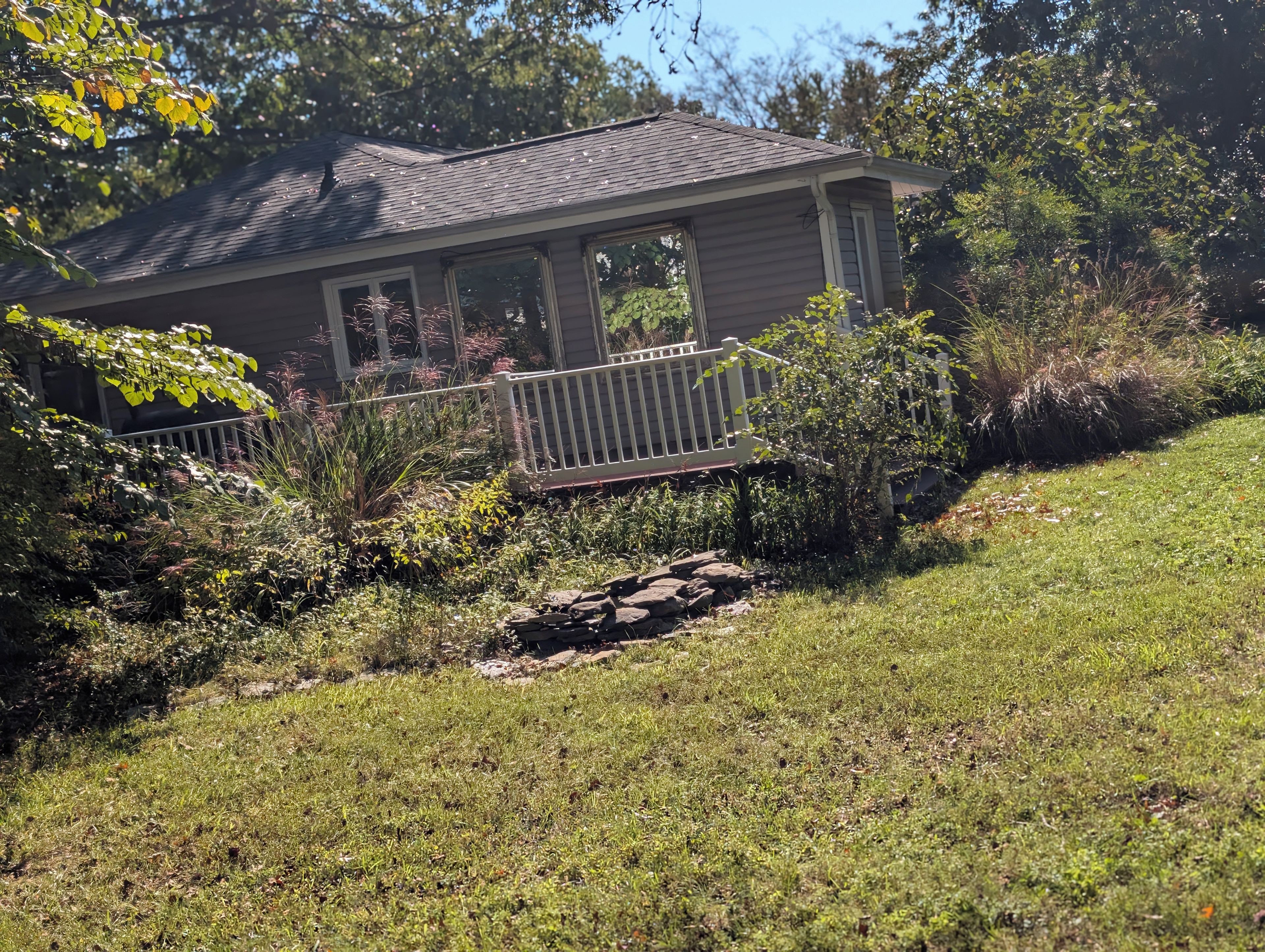 A house with a porch, surrounded by a well-maintained garden and a white fence.