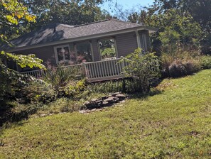 A house with a porch, surrounded by a well-maintained garden and a white fence.