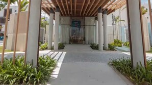 Un porticato con tetto in legno, colonne e un percorso lastricato che conduce all'ingresso di un edificio.