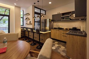 A modern kitchen with a central island, bar stools, a dining table, and a view of the outdoors. - Studio · Private balcony, parking, rooftop & BBQ (Ciudad de México)