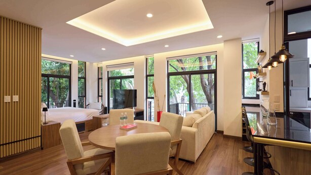Una habitación de hotel moderna con una cama grande, un comedor, un sofá y una cocina.