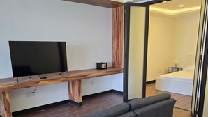 Moderni olohuone, jossa on litteänäyttöinen televisio, puukoristeinen seinä ja sohva.