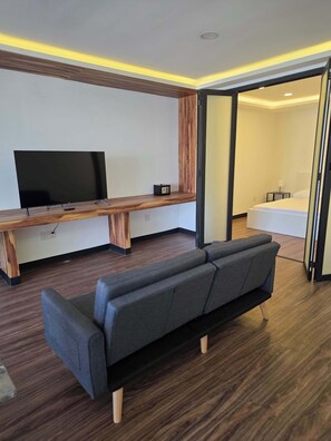 Ein modernes Wohnzimmer mit Flachbildfernseher, einer Wand im Holzdesign und einem Sofa.
